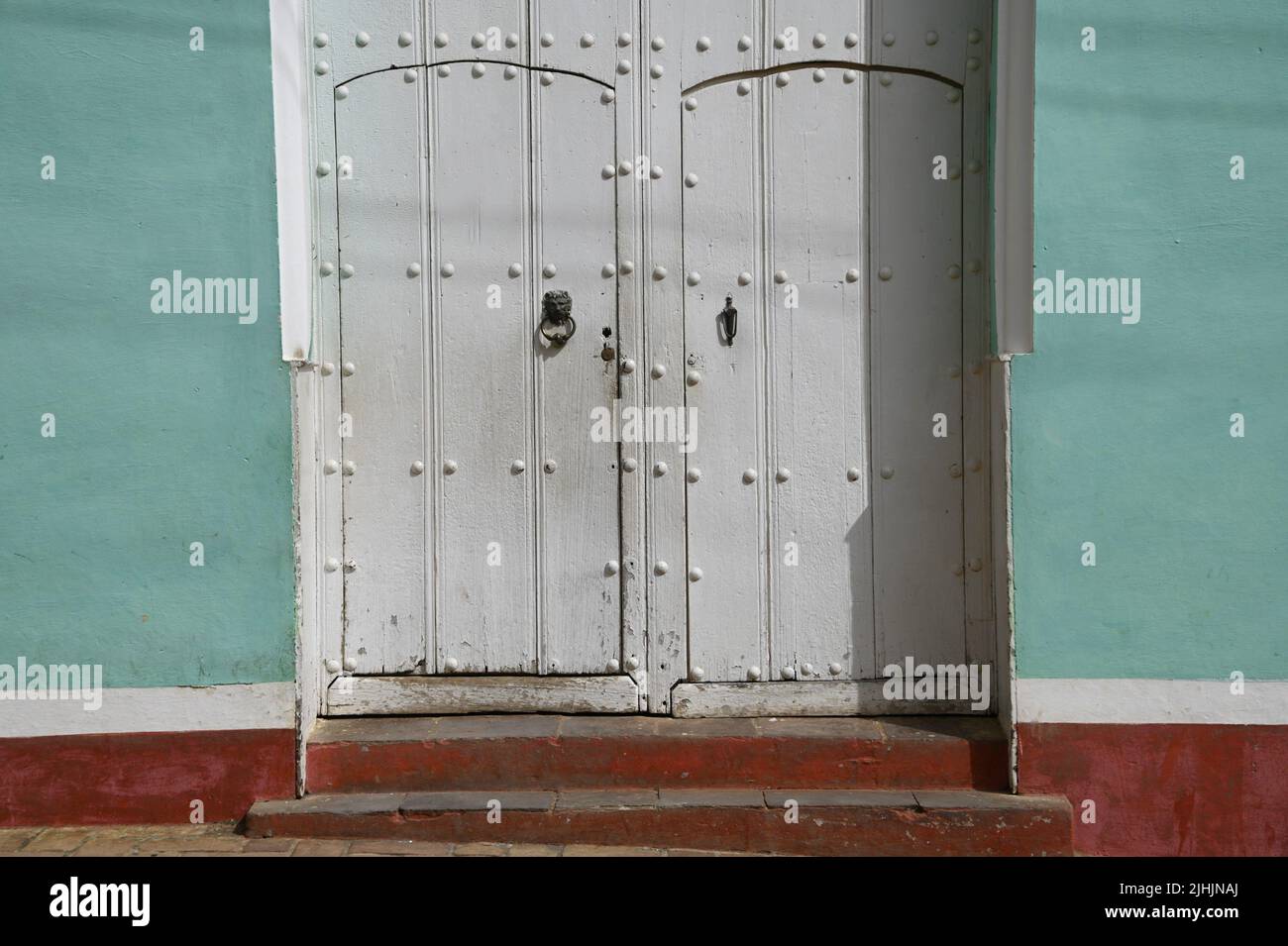 Antique whitewashed wooden door on a faded light green stucco wall with