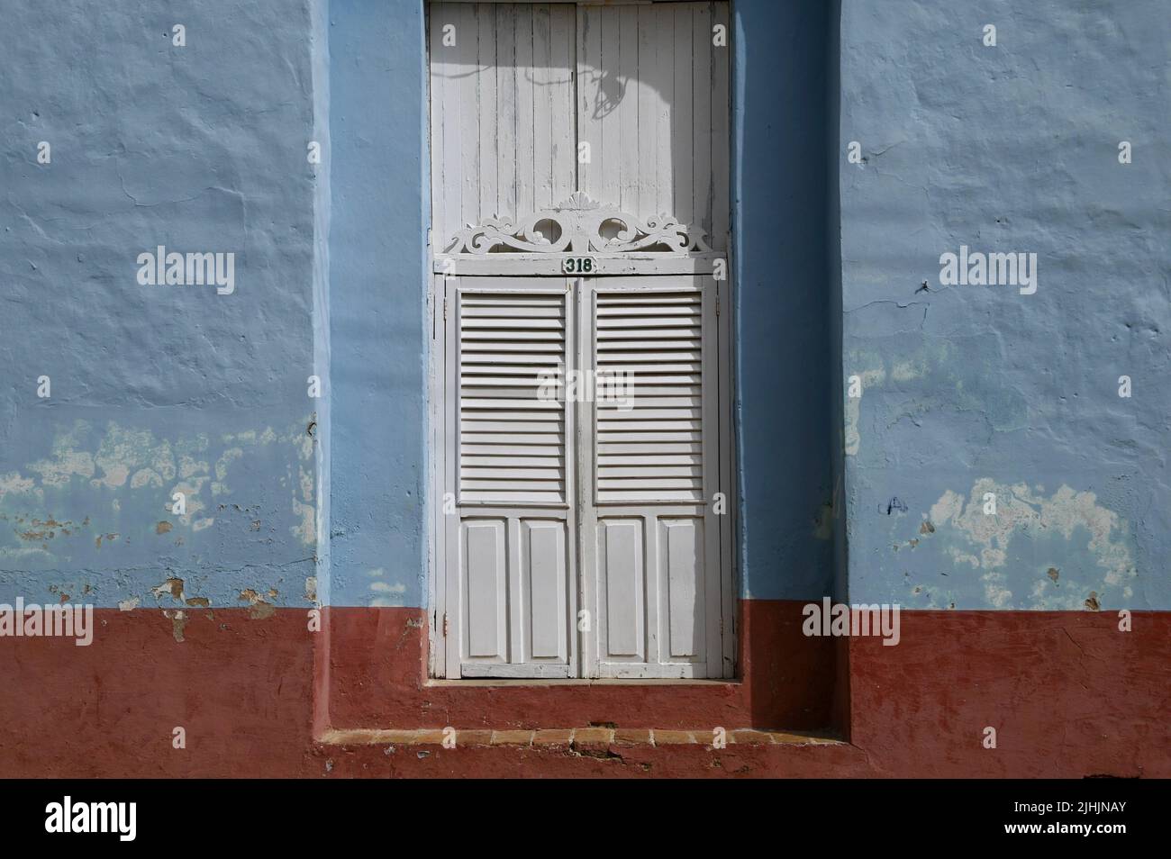 Antique whitewashed wooden door on a faded light blue stucco wall with