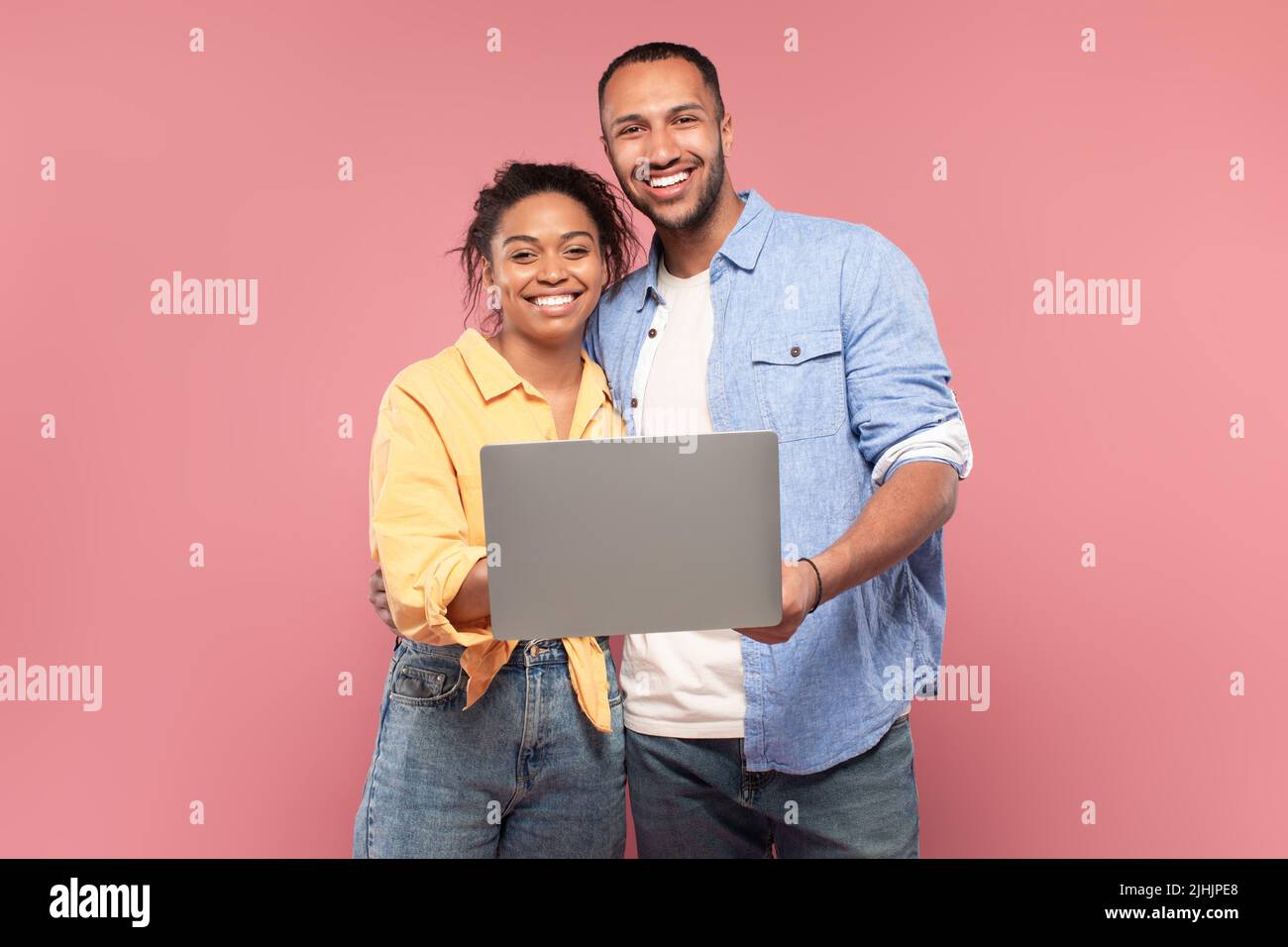 Portrait of happy african american couple holding and using laptop ...