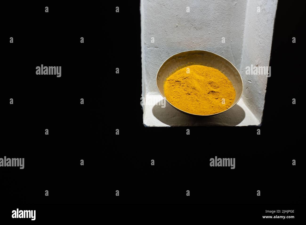 Yellow curry spices on a pot isolated on a black background Stock Photo
