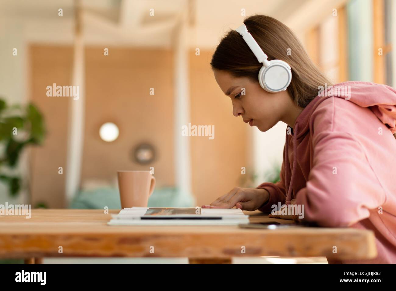 Smart focused teenager girl listening music in wireless headphones and