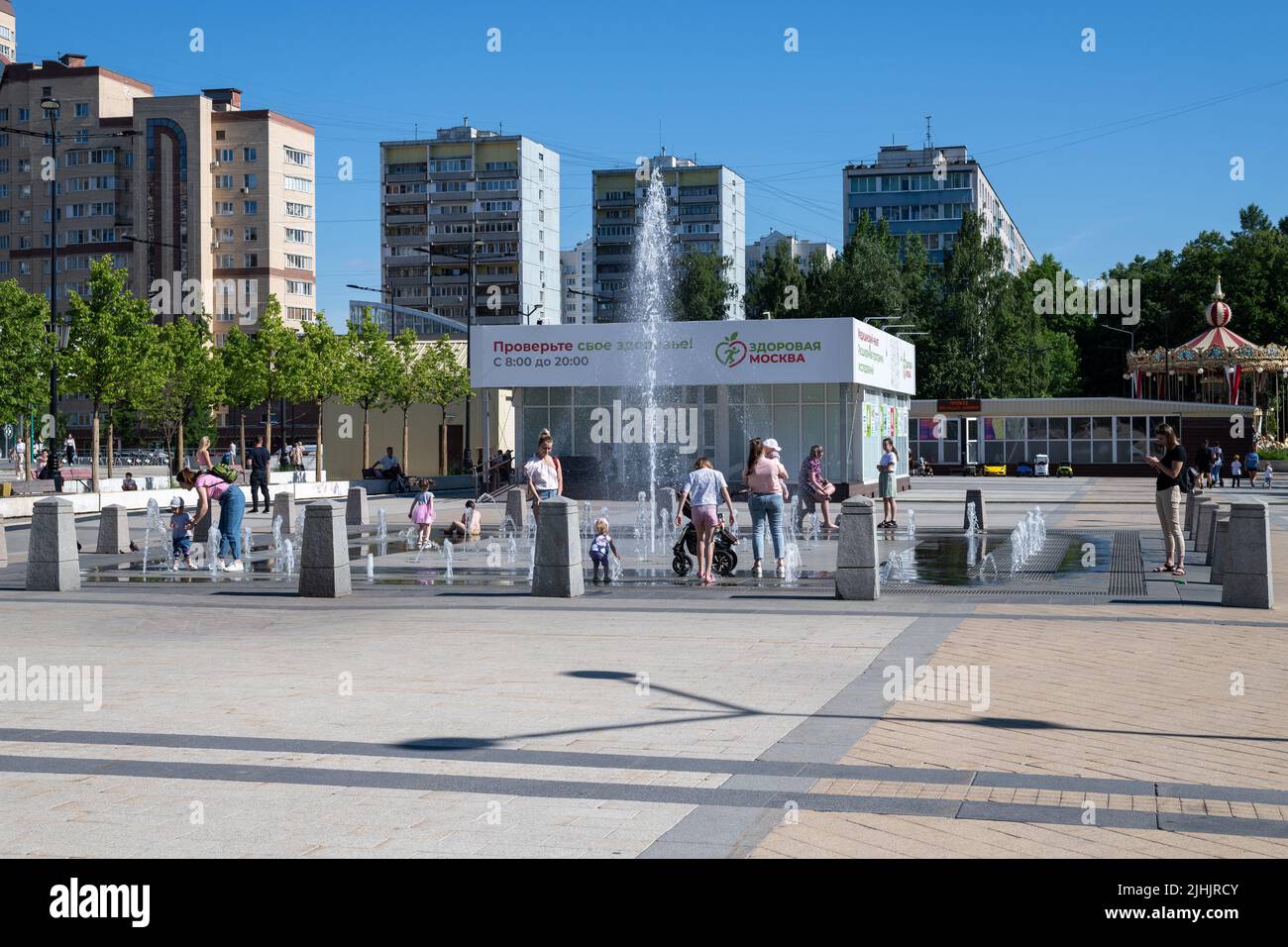 Moscow, Russia - June 23. 2022. Muscovites with children at fountain in the heat. Central square in Zelenograd Stock Photo