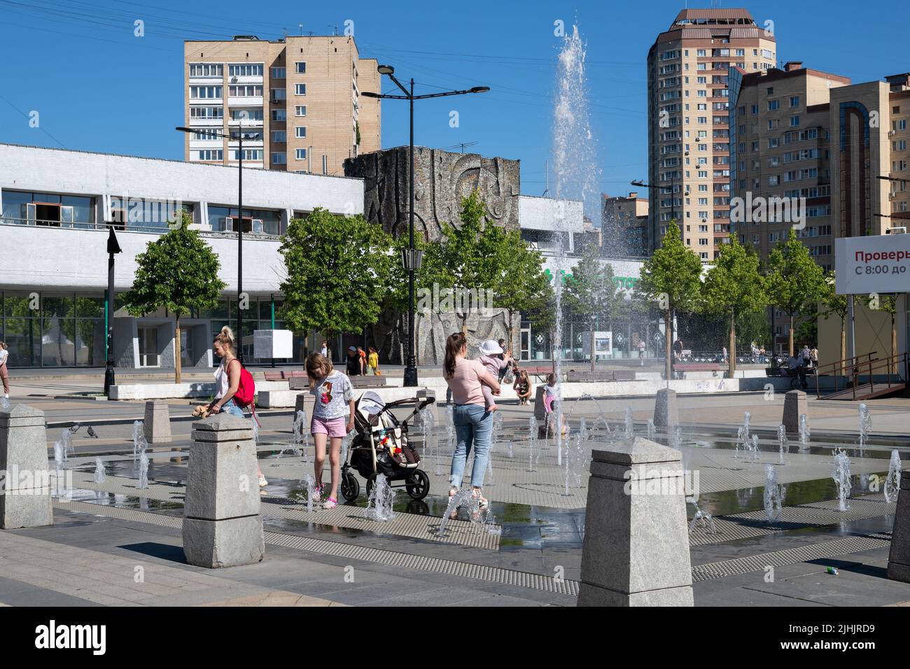 Moscow, Russia - June 23. 2022. Muscovites with children at fountain in the heat. Central square in Zelenograd Stock Photo