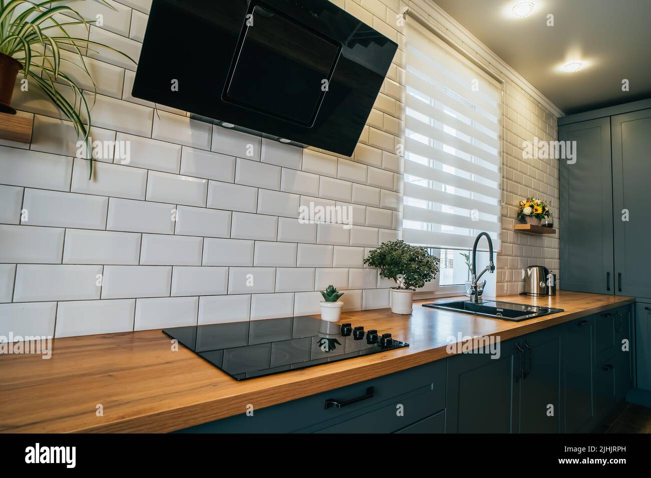 Countertop in modern kitchen with electric stove, extractor hood, sink