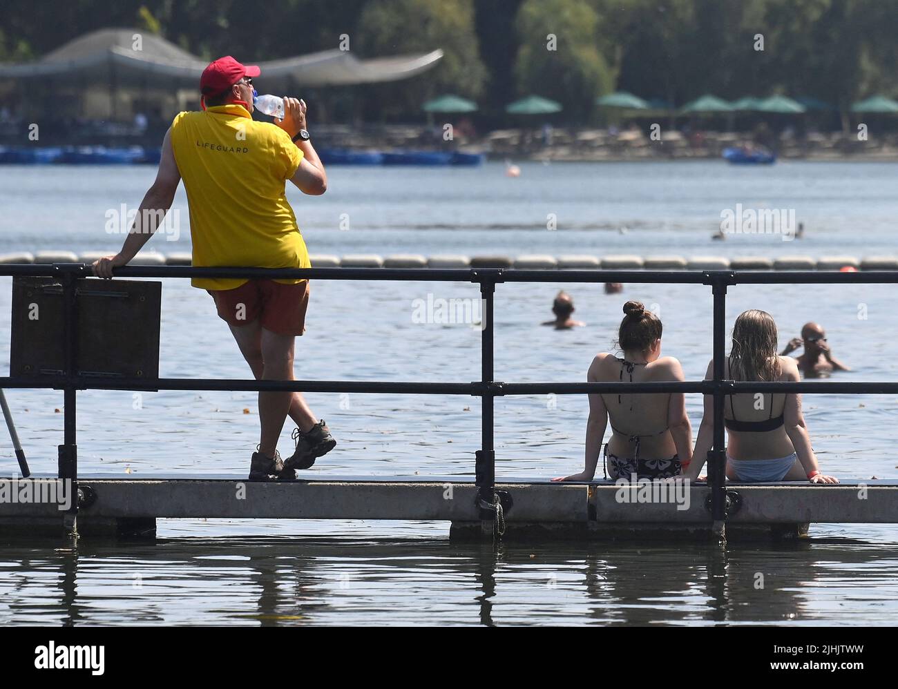 A lifeguard drinks water as people swim in the Serpentine Lake during hot weather in Hyde Park in London, Britain, July 19, 2022. REUTERS/Toby Melville Stock Photo