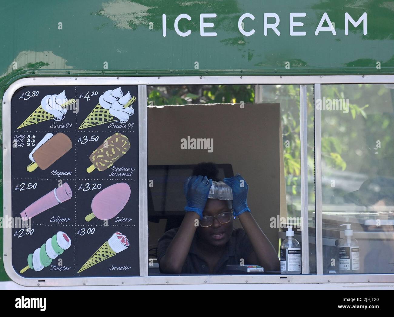 An ice cream vendor uses a bottle of water to cool down  during hot weather in Hyde Park in London, Britain, July 19, 2022. REUTERS/Toby Melville Stock Photo