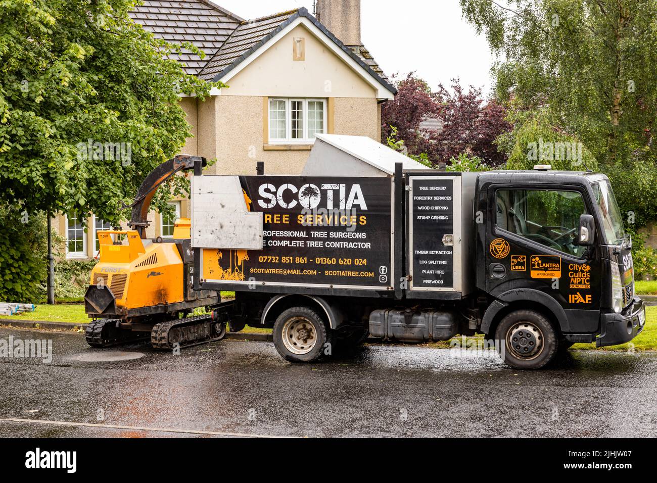Tree surgeon. Scotia professional tree services truck with hopper facility, with tracked chipping machine for shredding trees and shrubs in suburbs Stock Photo