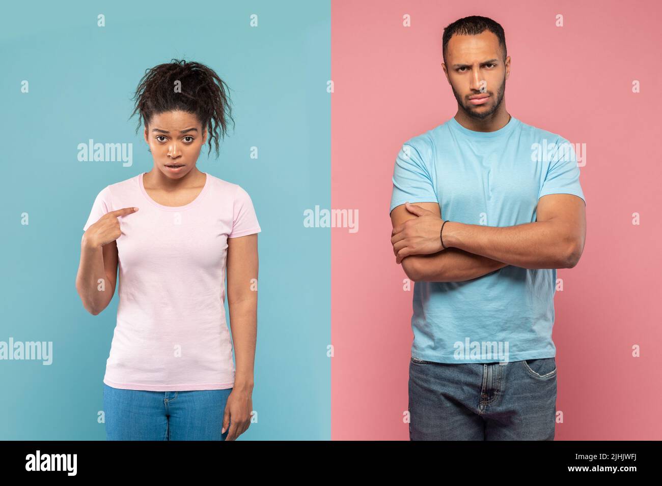 Displeased black lady pointing at herself with wonder, man standing with hands crossed after quarrel Stock Photo