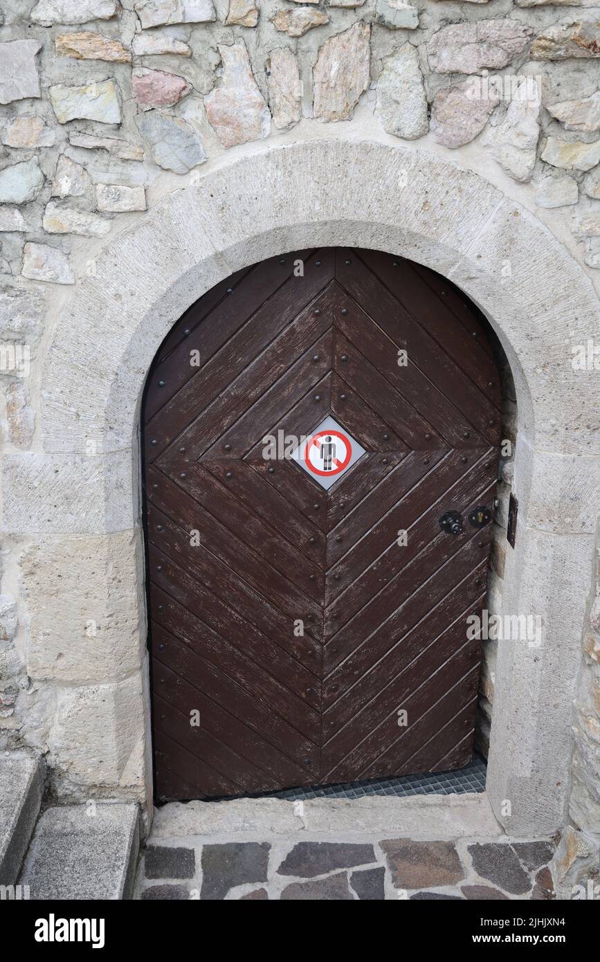 'No entry' pictogram sign on a wooden door in a stone wall Stock Photo