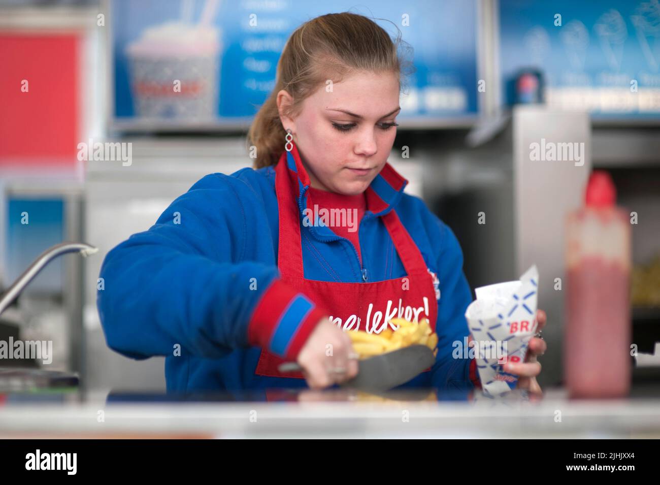 Rotterdam, Netherlands. Young adult female preparing an order Dutch Fries (Patat) for a customer at the Bram Ladage Stand Down Town Stock Photo