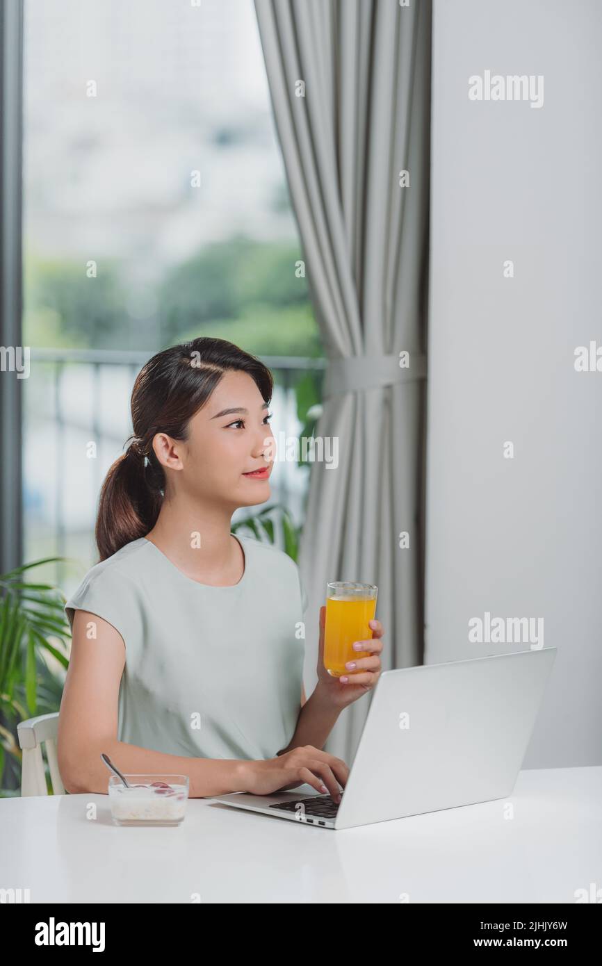 Beautiful woman relaxing with her laptop while holding a glass of orange juice Stock Photo