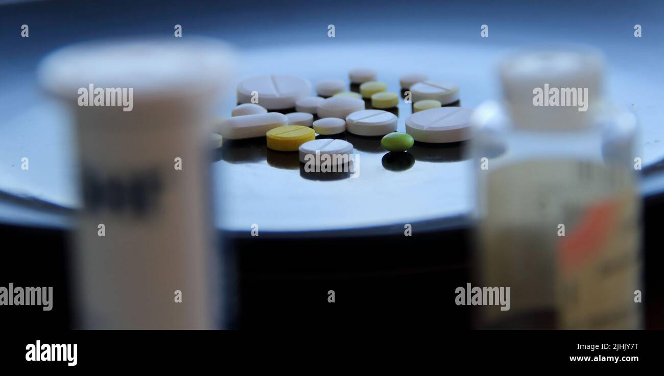 Colorful scattered tablets between pill bottles with soft focus Stock Photo