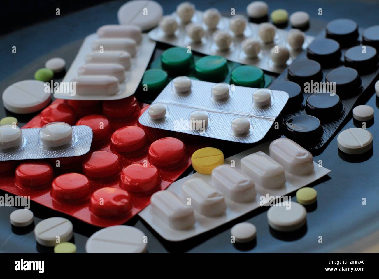 Tablets in different blisters and packages isolated on black surface Stock Photo