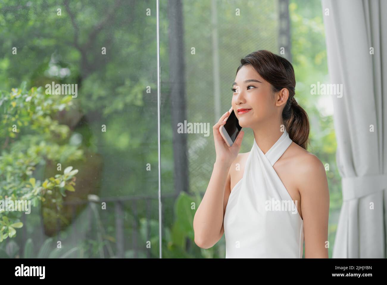 Portrait of beautiful young woman talking on the phone at home. Stock Photo
