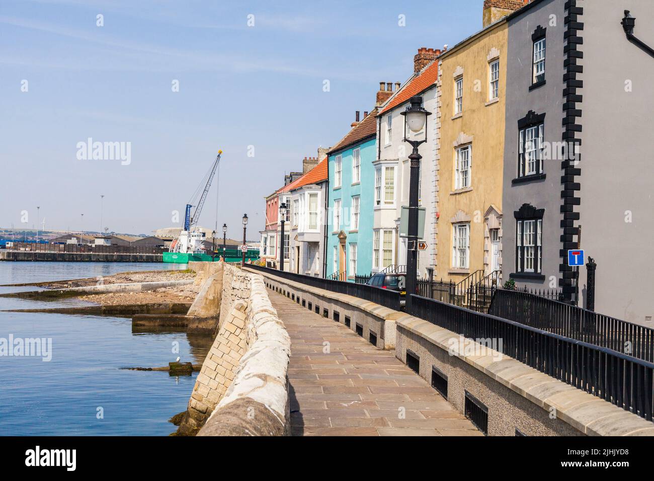 The beach,sea walls and houses with the cranes in the