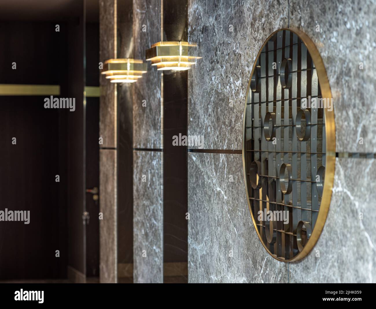 Reflection of stairs and wrought iron gating in mirror on marble wall. Modern interior of entrance in luxury residential apartment building. Stock Photo