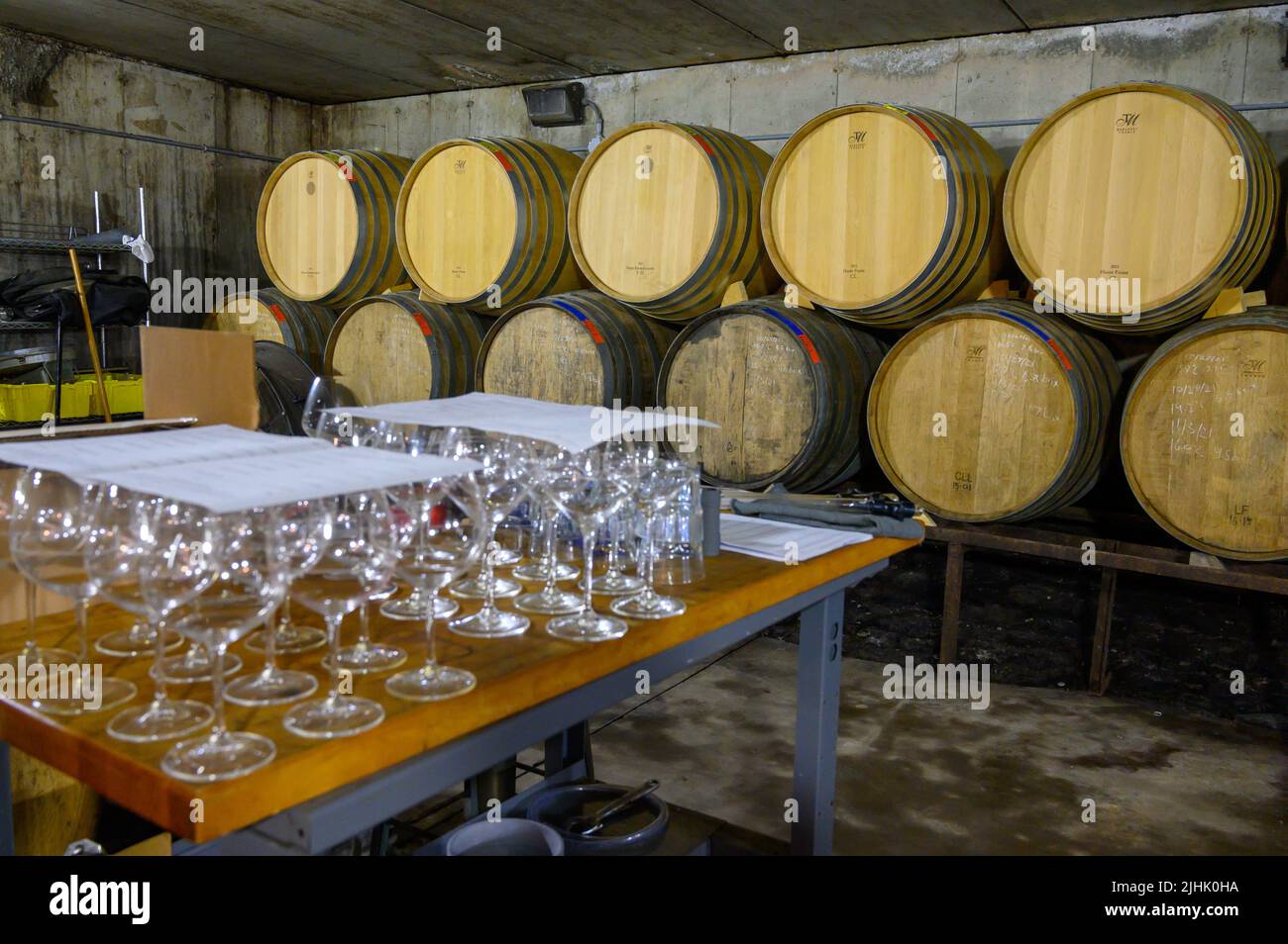 Stacked oak barrels with wine and glasses ready for tasting in the