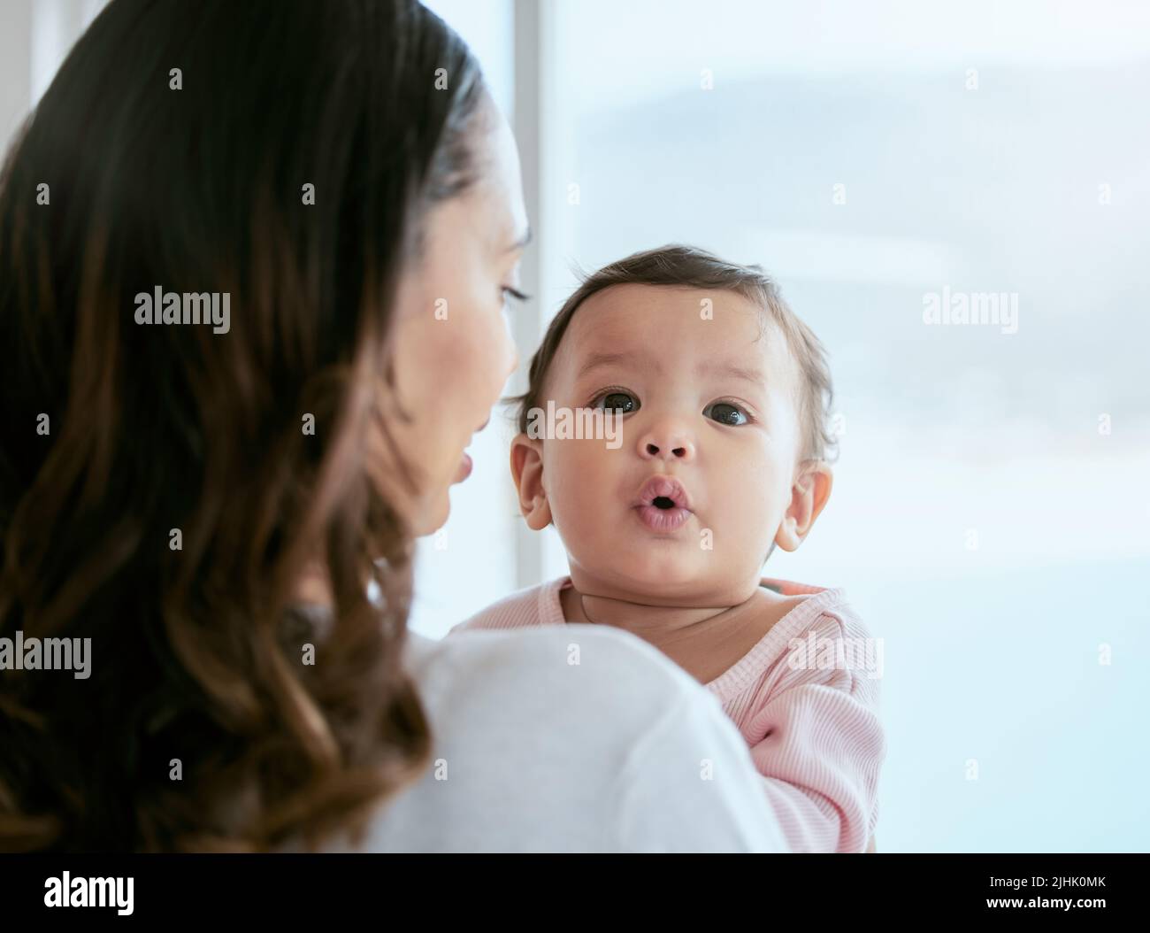 If I move my mouth, it makes a sound. a mother holding her baby daughter at home. Stock Photo