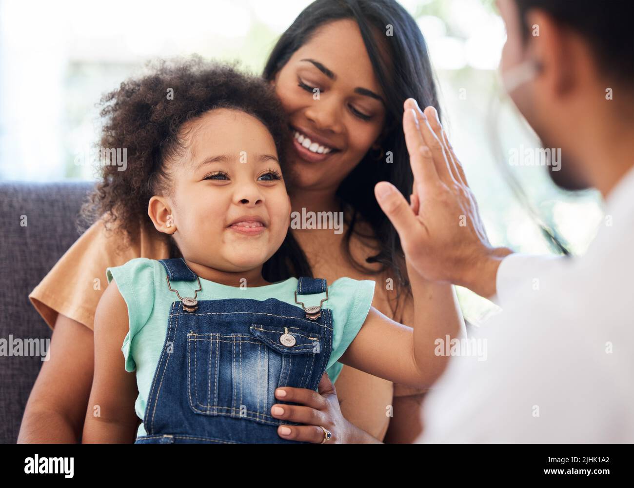 What a good checkup. a little girl sitting on her mothers lap while being examined by her doctor. Stock Photo