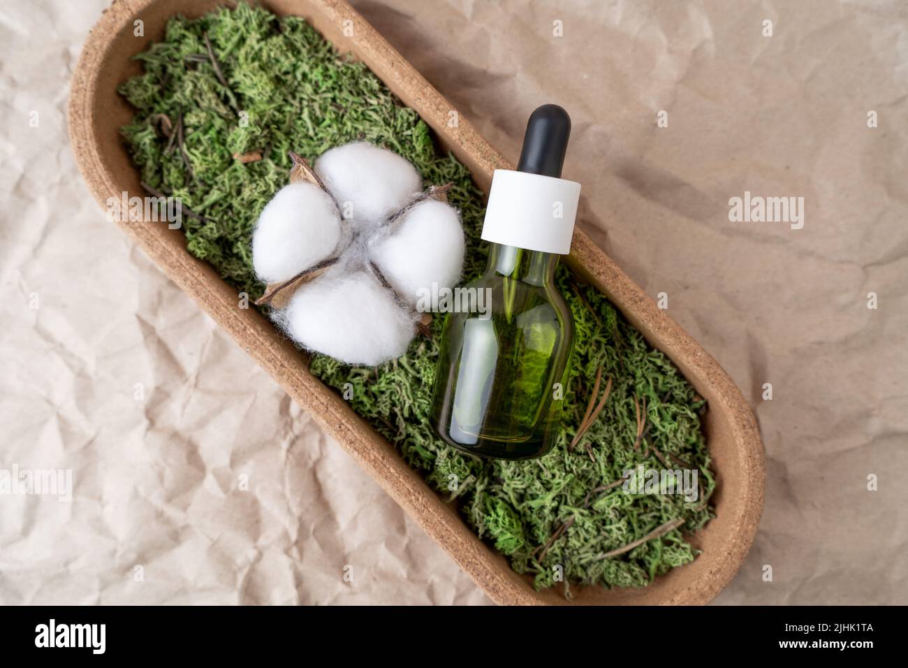 A green dropper bottle of face serum or natural oil lying on a moss Stock Photo