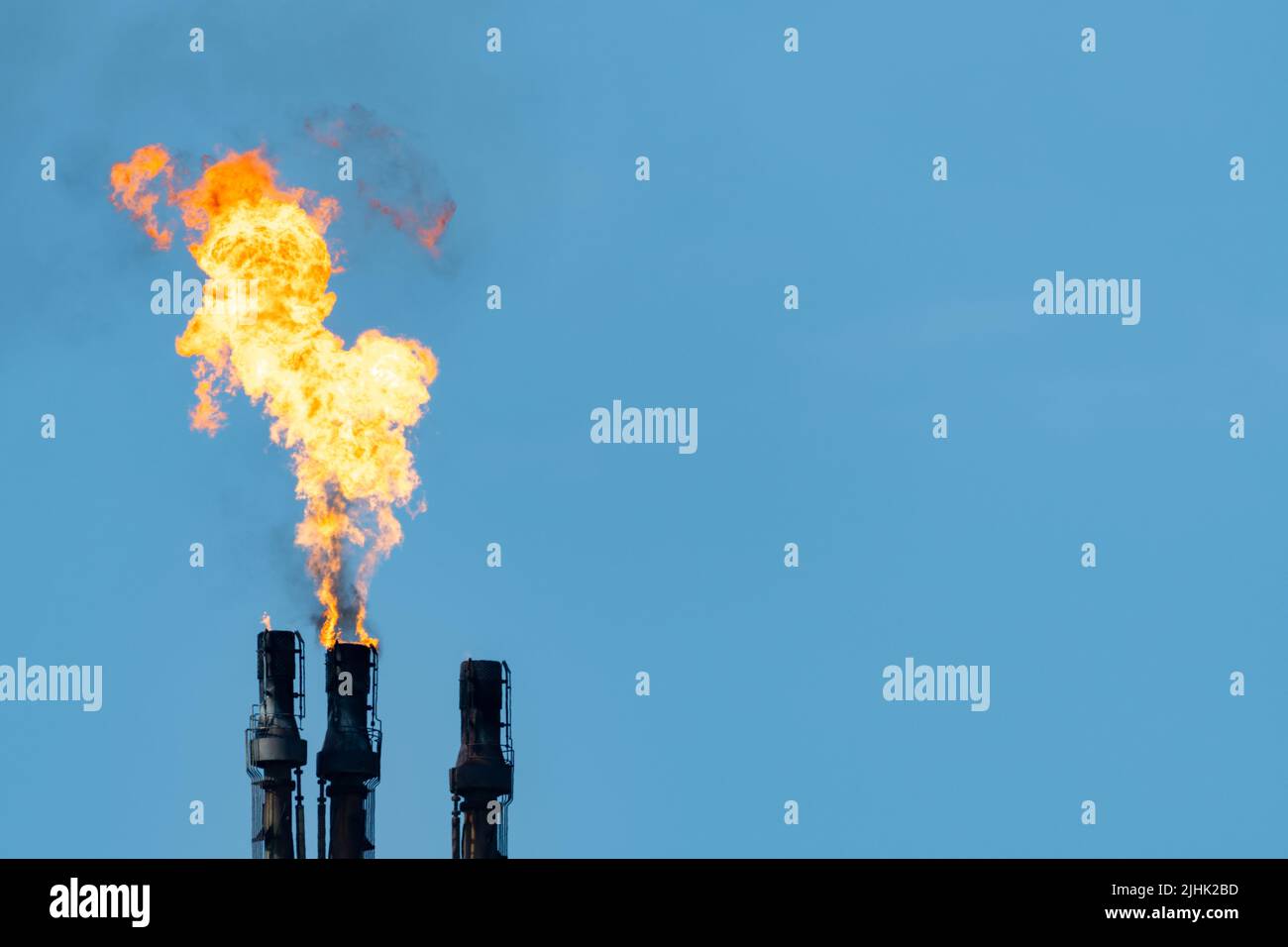Oil refinery gas flare, flare stack burning off excess gas. Copy space right. Oil refinery flame, flare, flaring, chimney, pollution, smokestack. UK Stock Photo