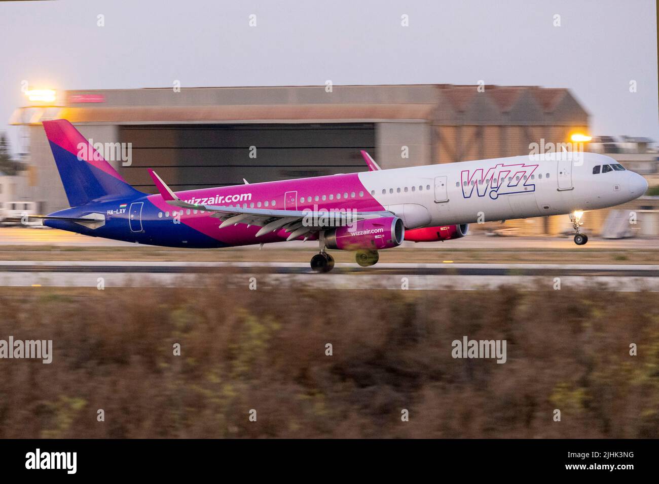 Wizz Air Airbus A321-231 (REG: HA-LXV) touching down after sunset runway 13. Stock Photo