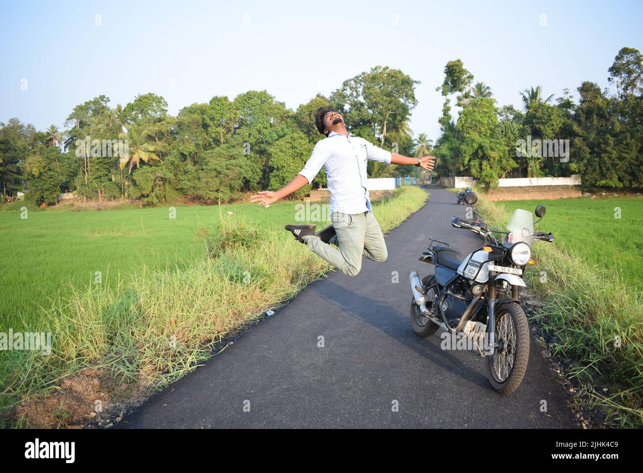 A man posing for photo with motorbike near paddy field Stock Photo