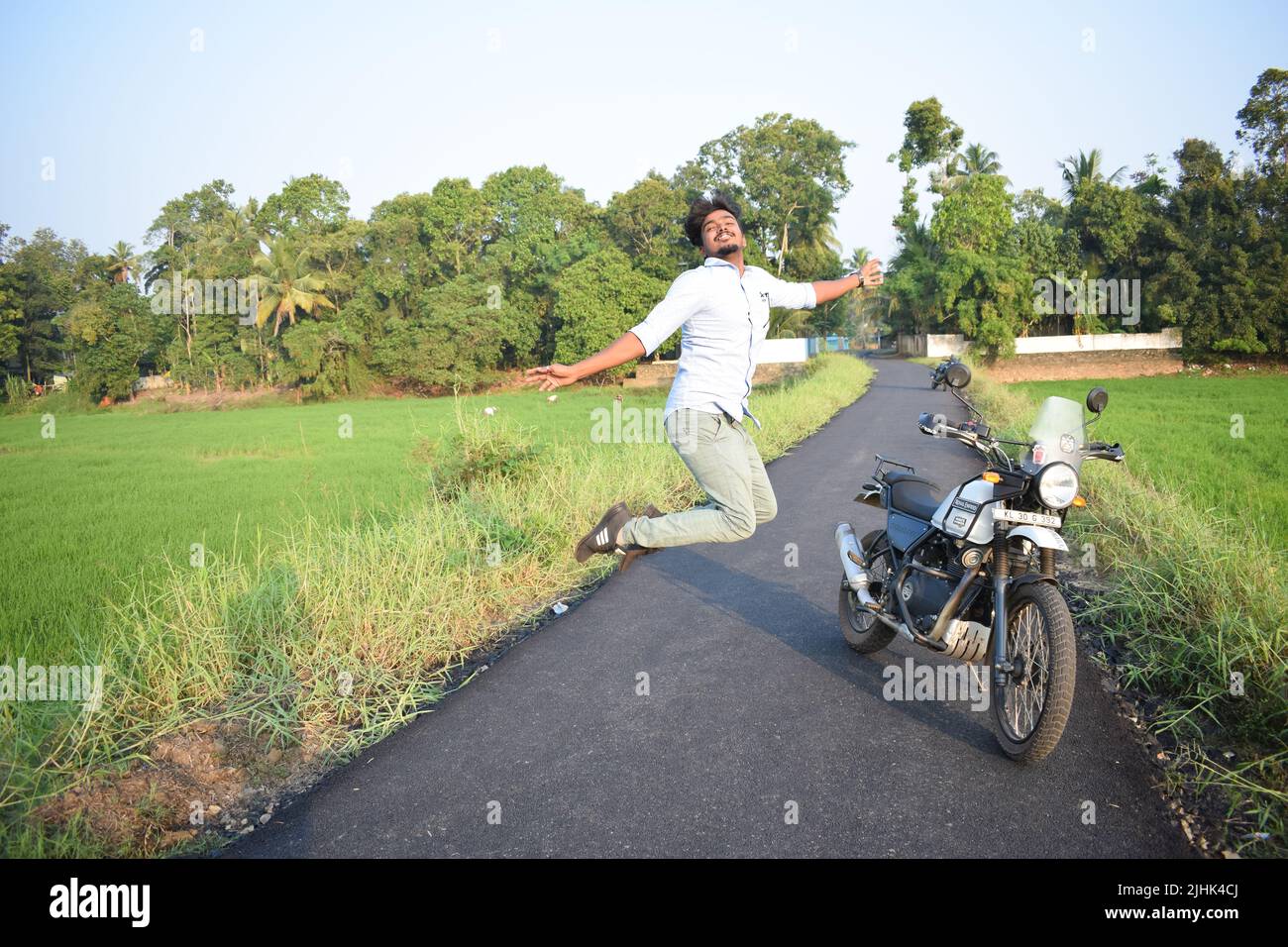 A man posing for photo with motorbike near paddy field Stock Photo