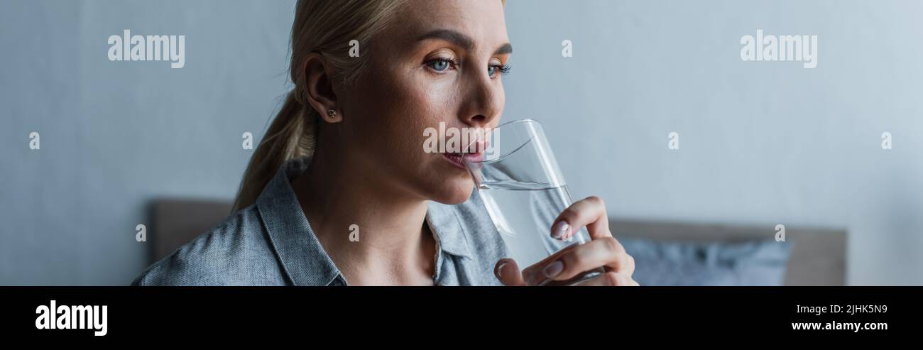 blonde woman with menopause drinking fresh water from glass, banner Stock Photo