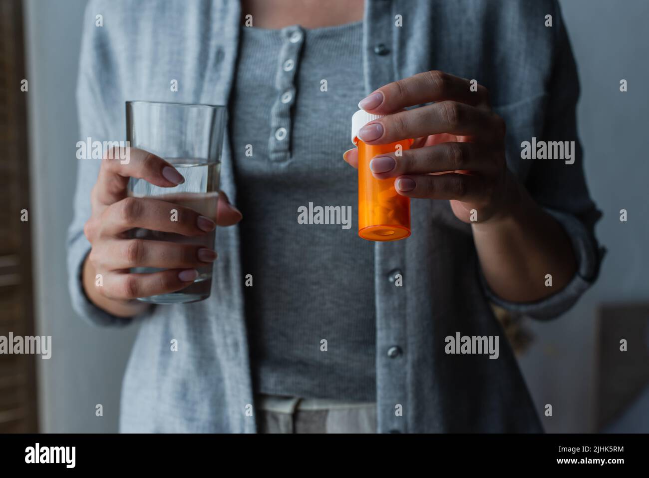 cropped view woman with menopause holding glass of water and medication Stock Photo
