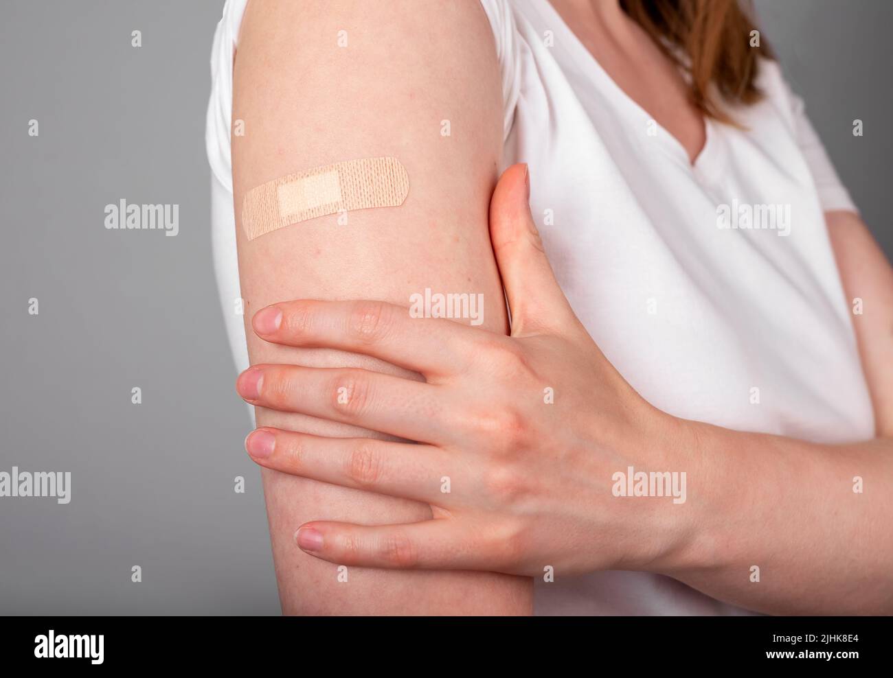 Woman holding shoulder with medical plaster. Vaccination, health care and medicine concept. Vaccinated person receiving flu or Coronavirus vaccine. High quality photo Stock Photo
