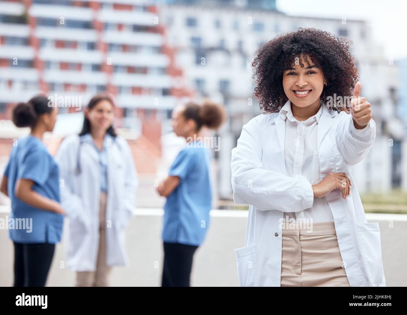 Portrait of a happy young mixed race doctor gesturing thumbs up with ...