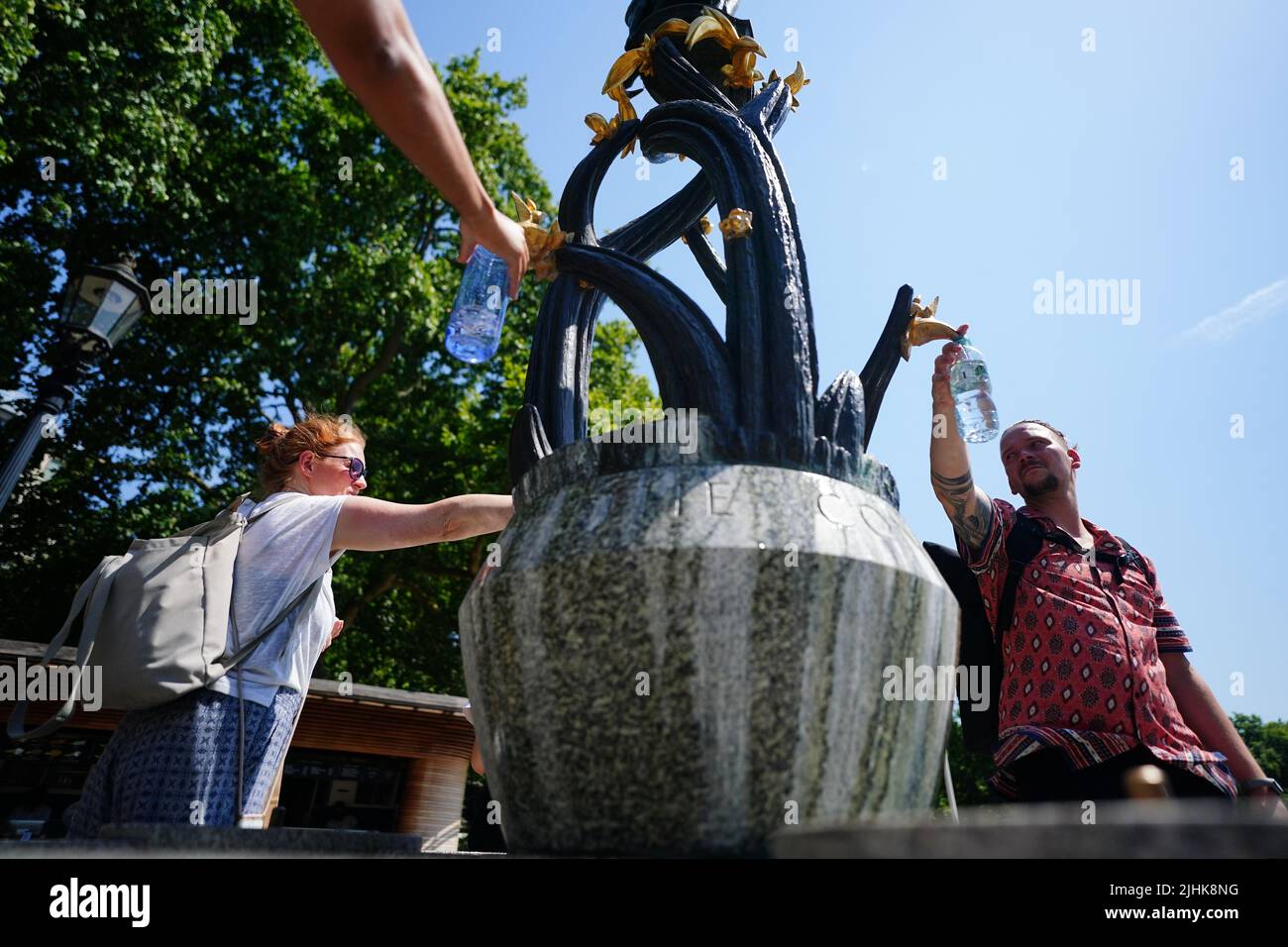People fill up bottles from a drinking fountain in Green Park, central London. Temperatures have reached 40C for the first time on record in the UK, with 40.2C provisionally recorded at London Heathrow, the Met Office has said. Picture date: Tuesday July 19, 2022. Stock Photo