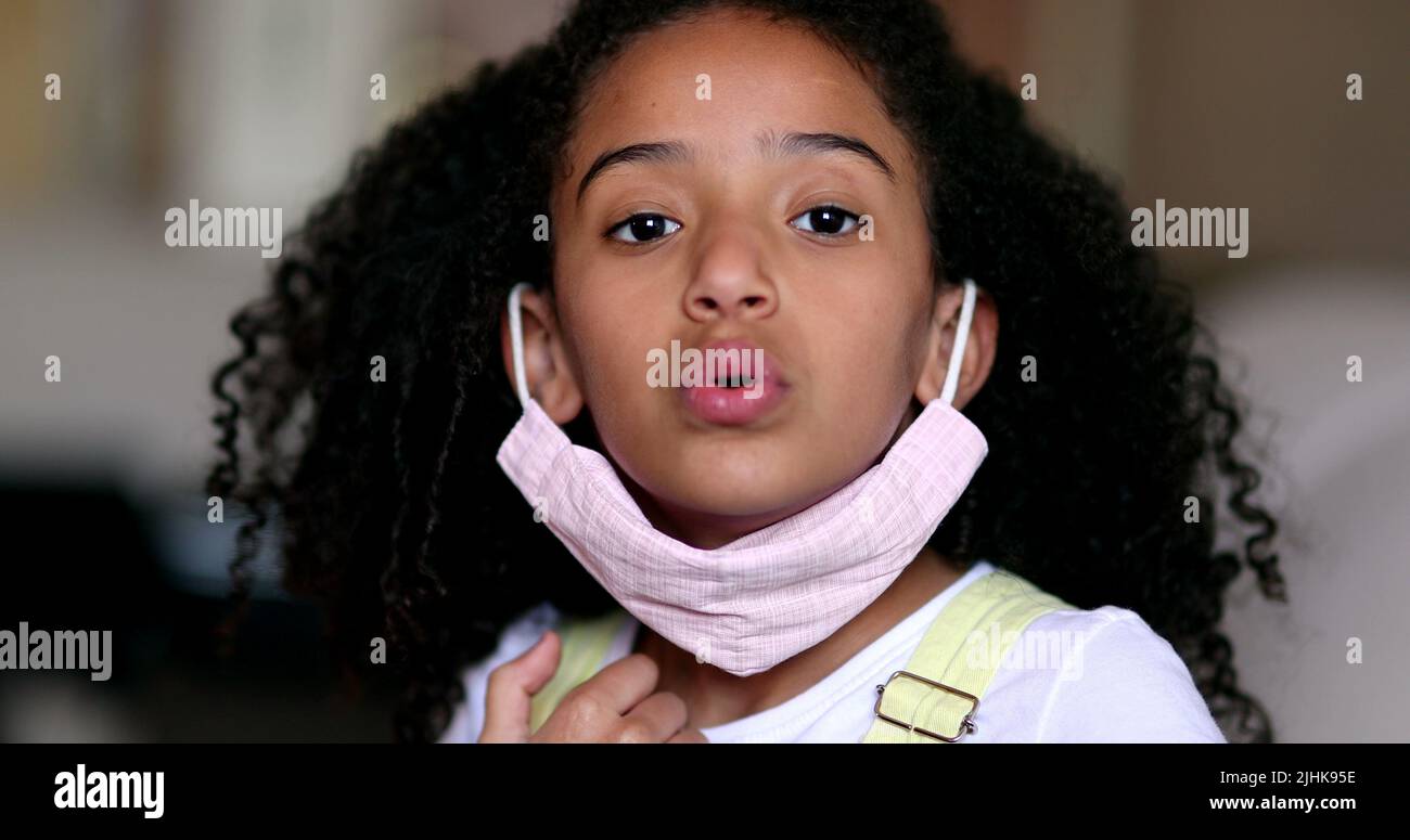 Girl removing covid face mask, little child takes off mask Stock Photo