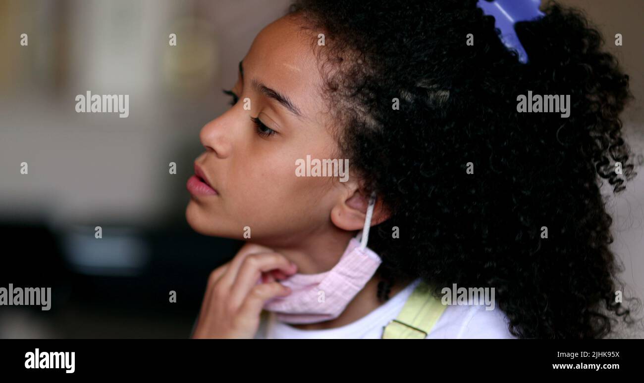 Girl removing covid face mask, little child takes off mask Stock Photo