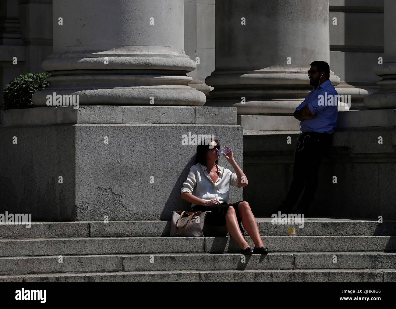 A woman drinks water during the hot weather in the City of London financial district, London, Britain, July 19, 2022. REUTERS/Toby Melville Stock Photo