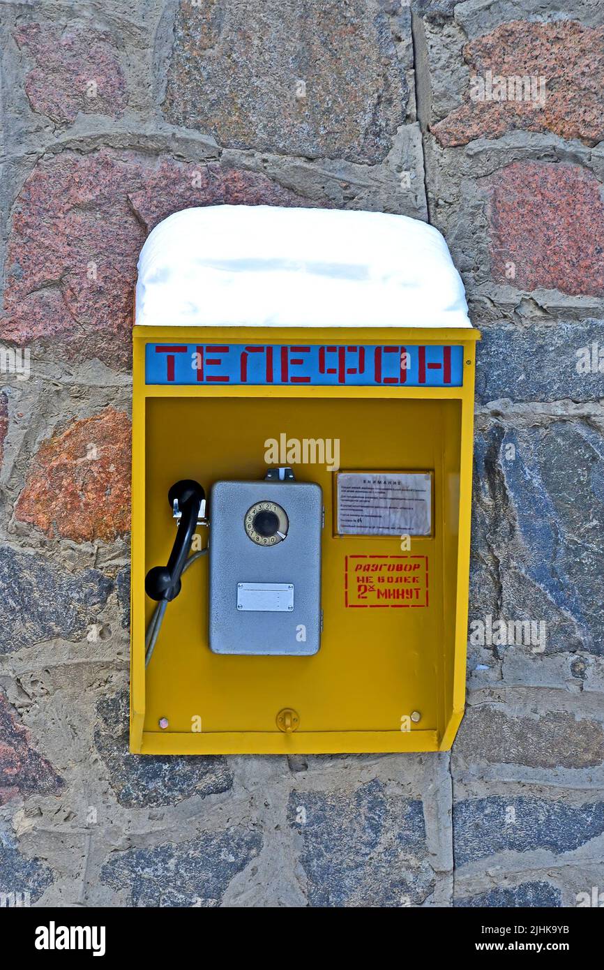 vintage soviet street telephone cabin on the stone wall under snow, retro wired technology diversity Stock Photo