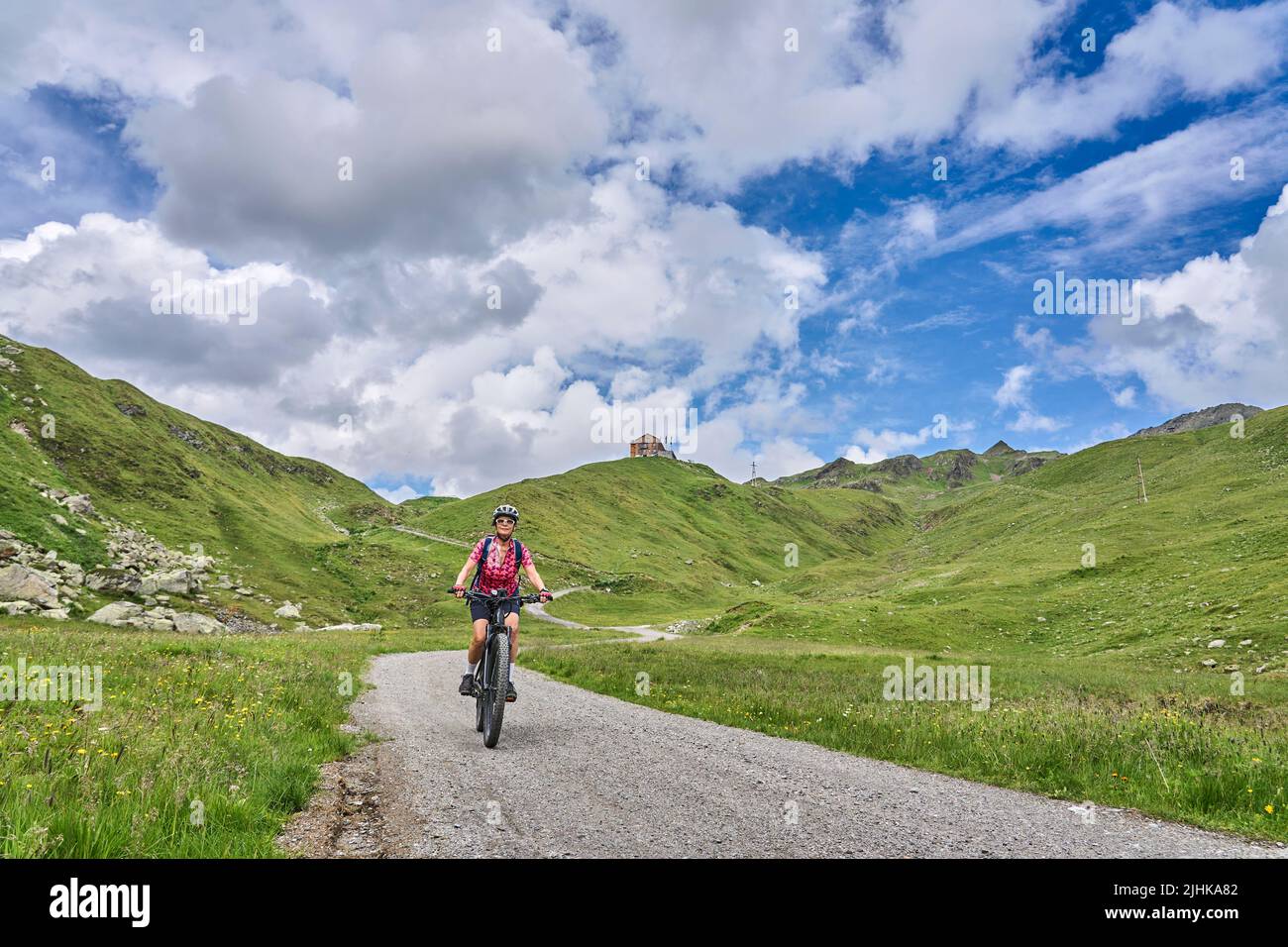 nice active senior woman riding her electric mountain bike in the silvretta mountain range above barrier lake Kopssee,near Gaschurn, Tyrol, Austria Stock Photo