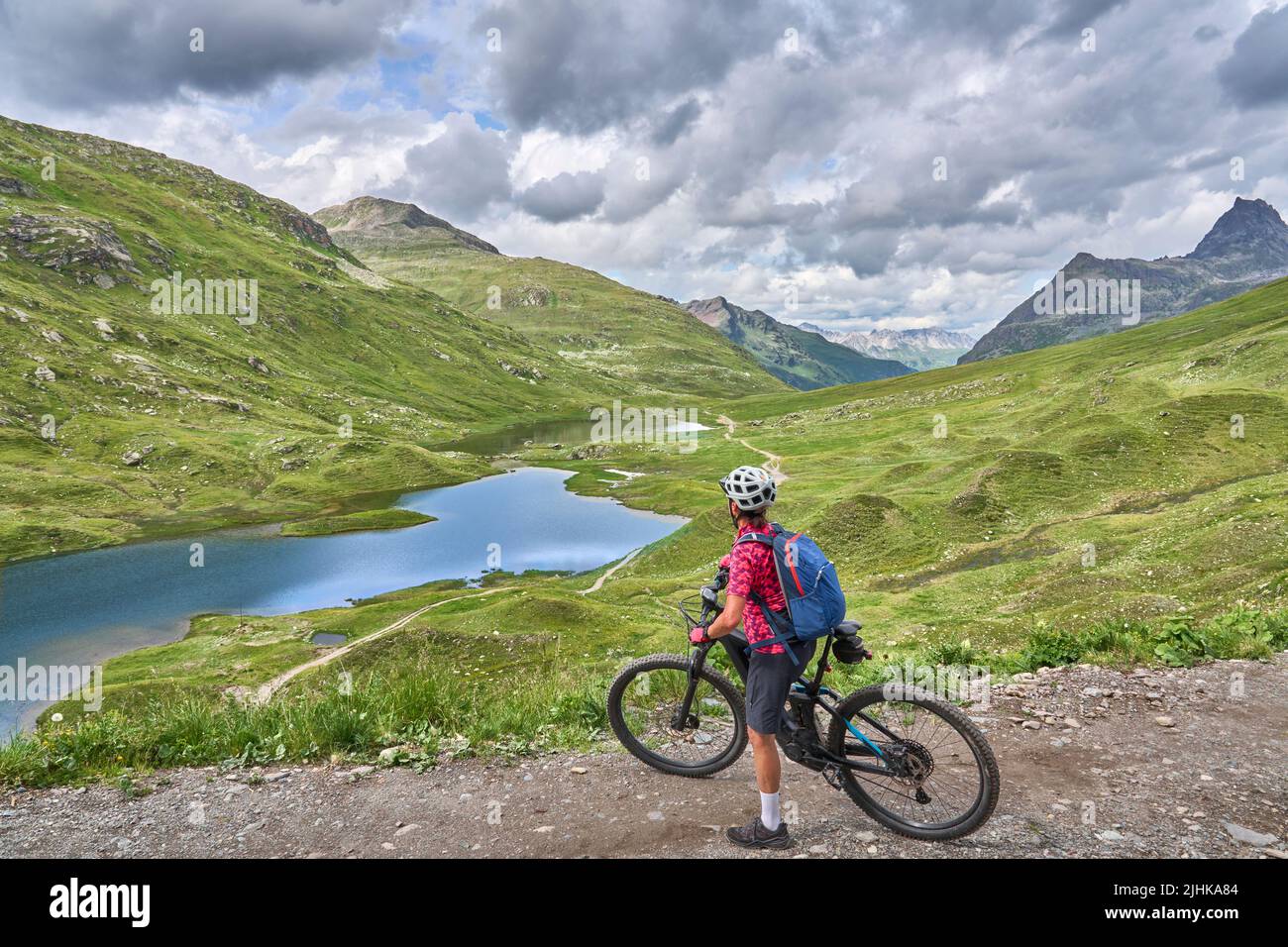 nice active senior woman riding her electric mountain bike in the silvretta mountain range above barrier lake Kopssee,near Gaschurn, Tyrol, Austria Stock Photo