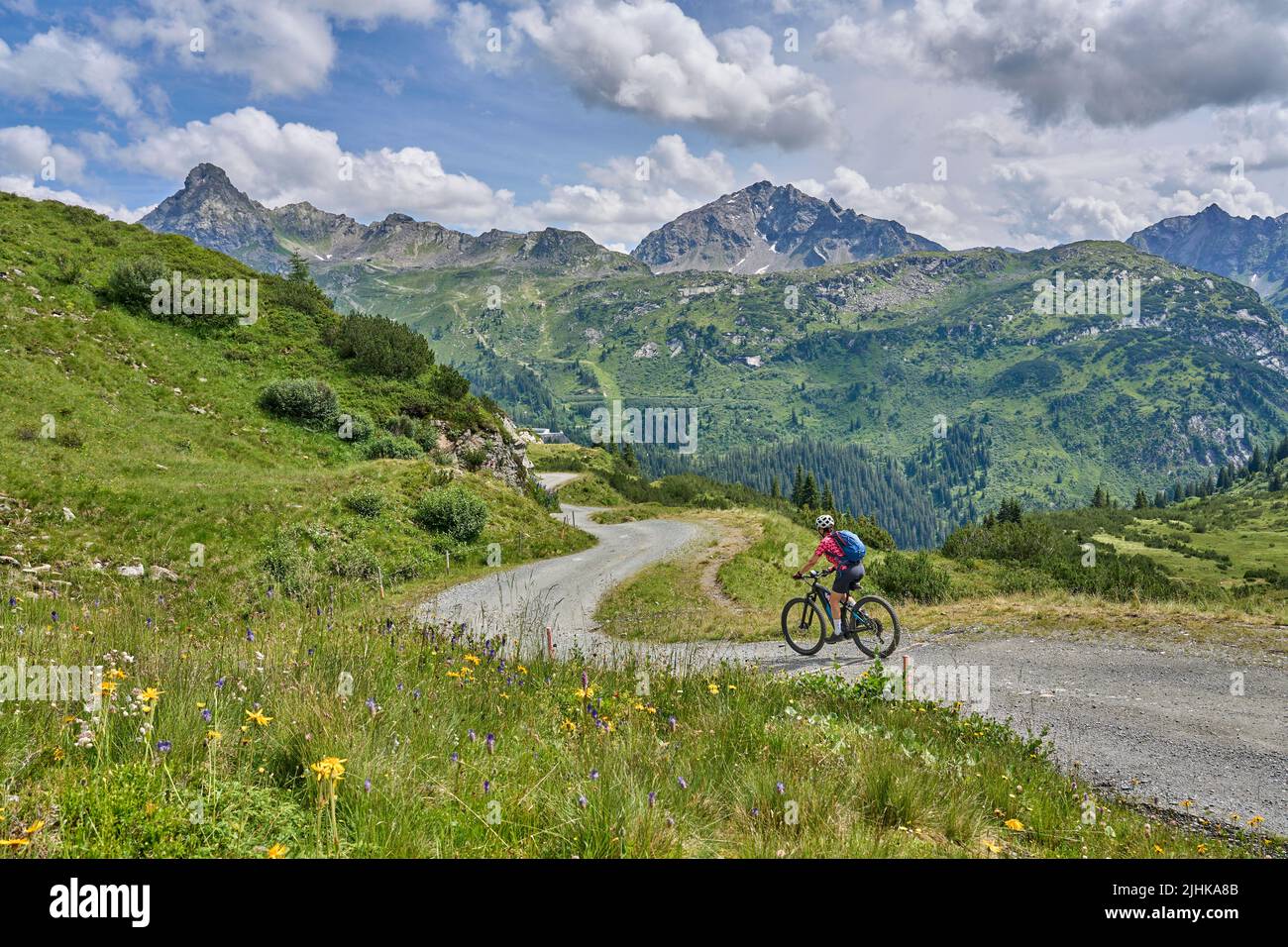 nice active senior woman riding her electric mountain bike in the silvretta mountain range above barrier lake Kopssee,near Gaschurn, Tyrol, Austria Stock Photo