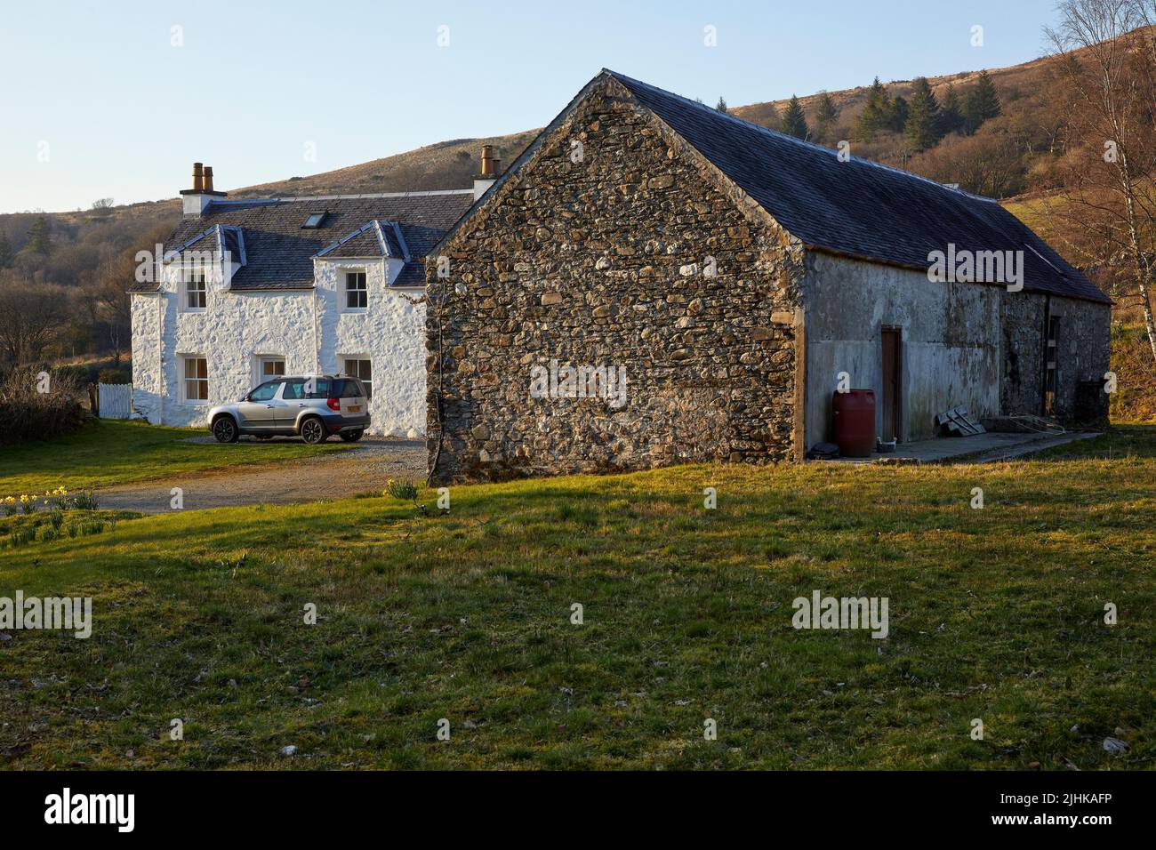 Early evening and the sun picks out detail on the white painted Inverglen Farmhouse and stone barn conversion to holiday accommodation. Strachur. Argy Stock Photo