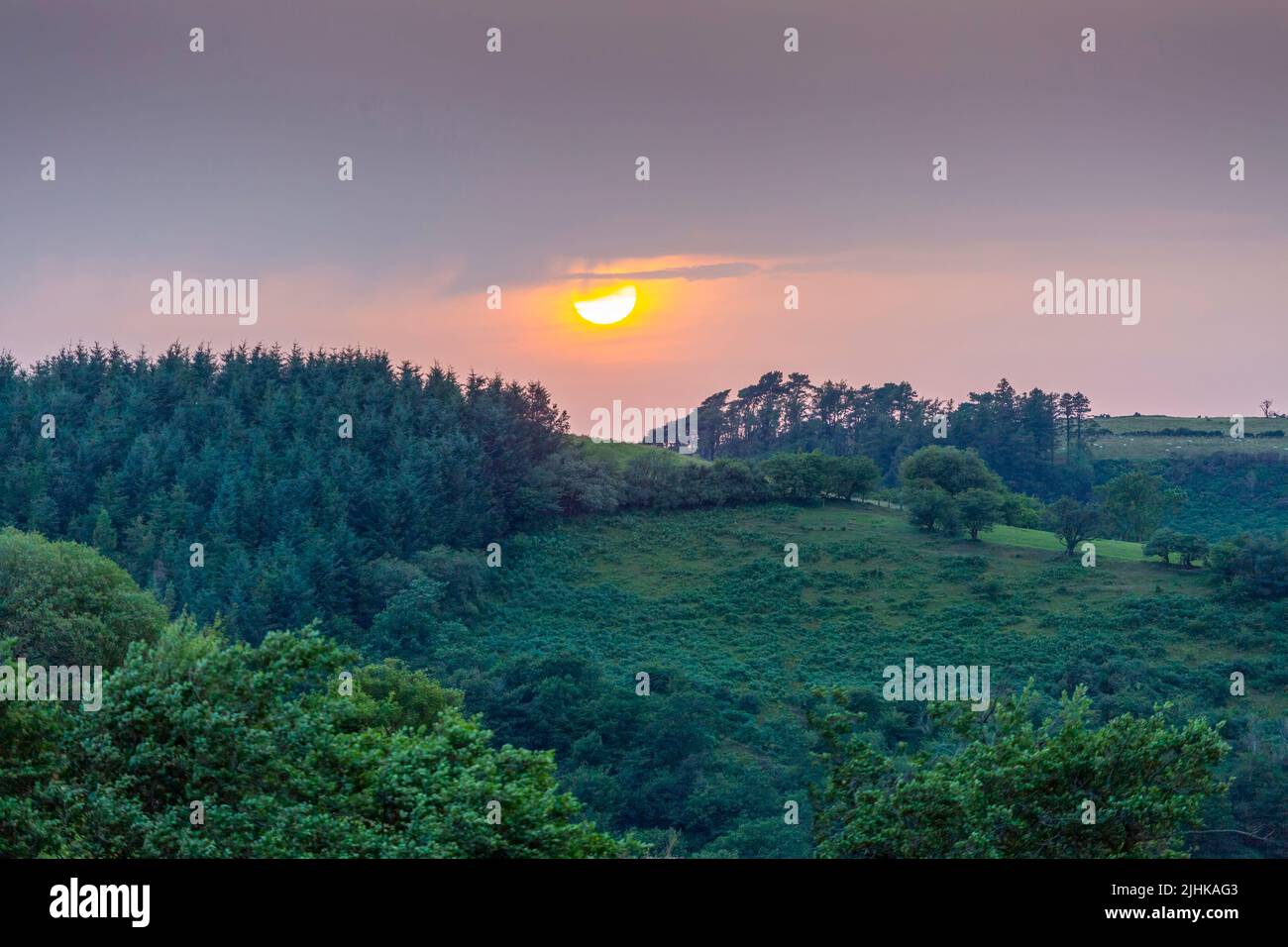 A ball of sun setting over the fields in the Brecon Beacons, South Wales UK Stock Photo