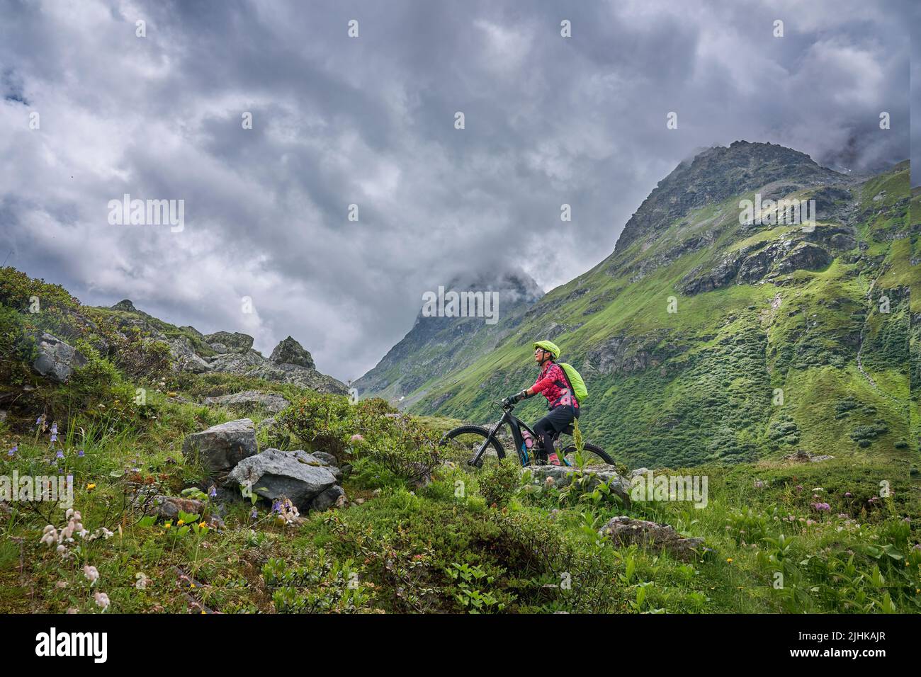 nice active senior woman riding her electric mountain bike in the silvretta mountain range above barrier lake Kopssee,near Gaschurn, Tyrol, Austria Stock Photo