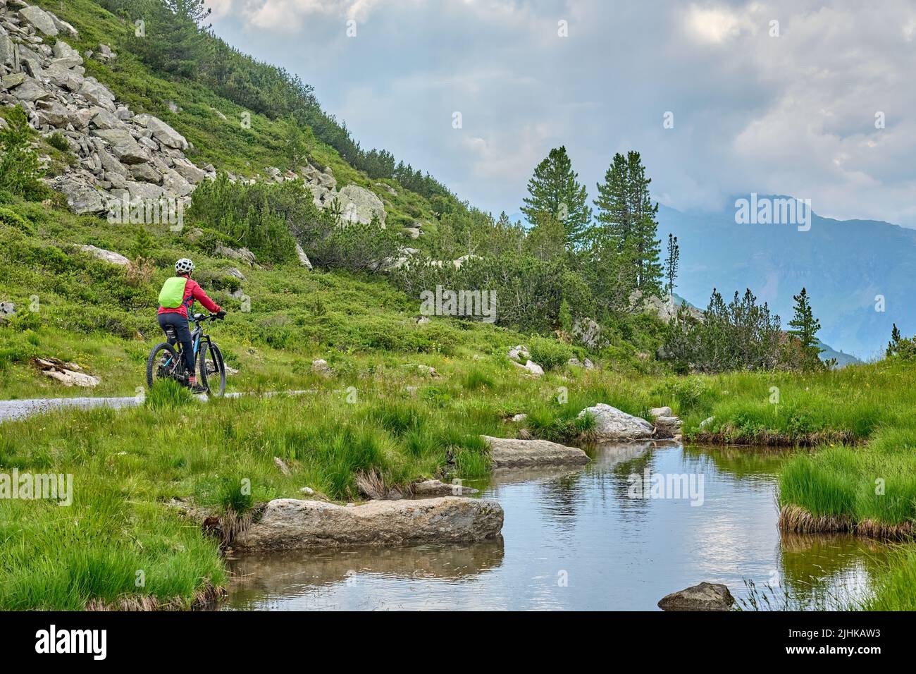 nice active senior woman riding her electric mountain bike in the silvretta mountain range above barrier lake Kopssee,near Gaschurn, Tyrol, Austria Stock Photo
