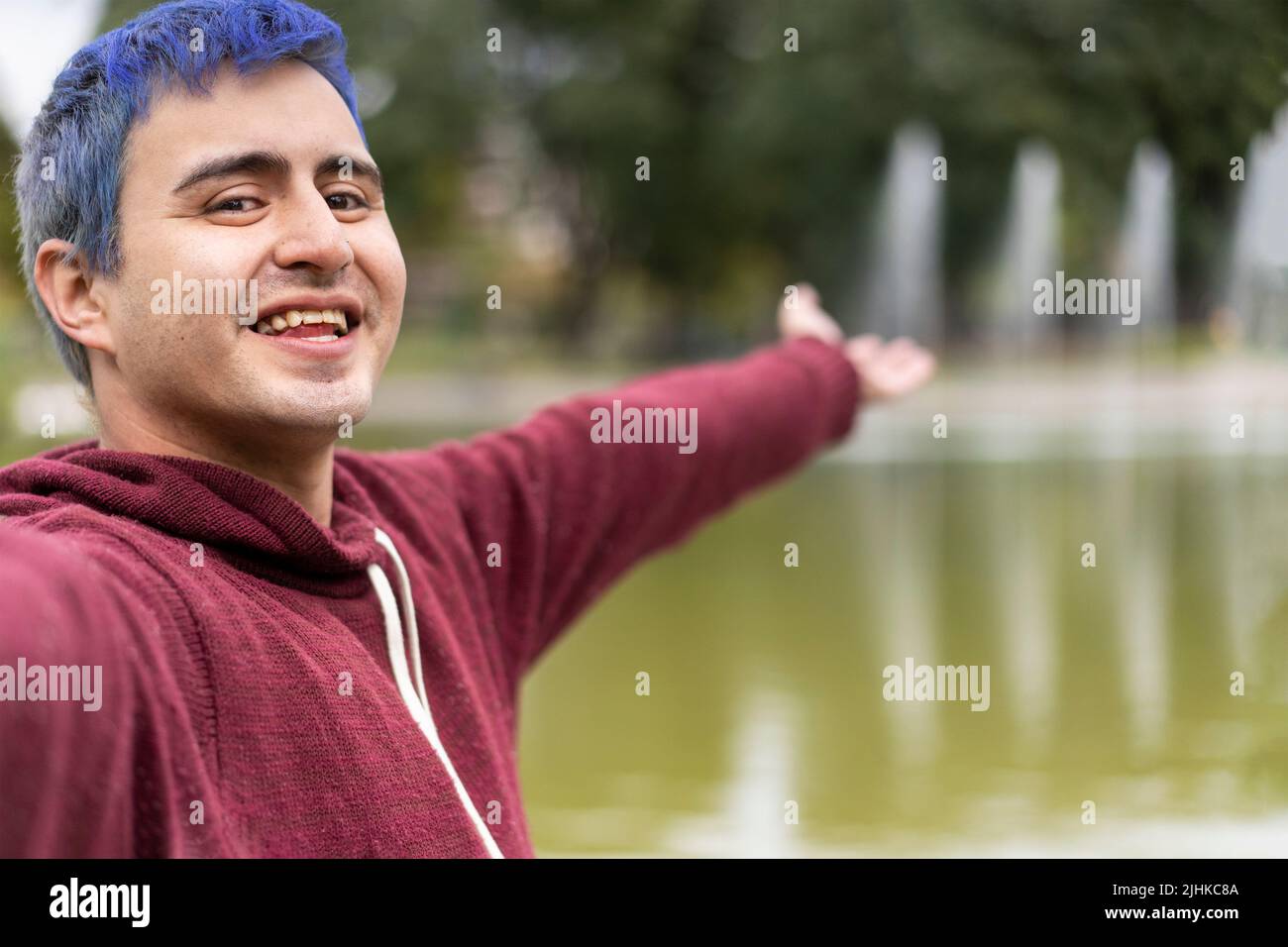 Active young Caucasian latin gay man taking selfie showing around at a lake. Outdoor adventure concept. Stock Photo