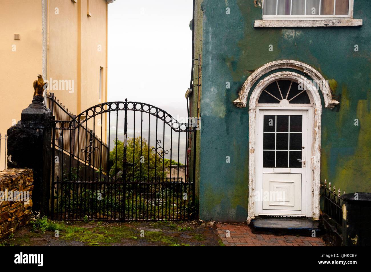 Simple door pediment and arched wrought iron iron gate define space and