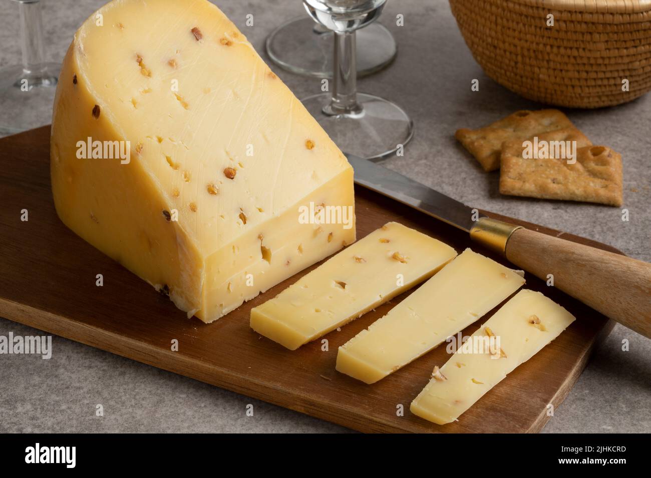 Piece of Fenugreek cheese and slices on a cutting board close up Stock Photo