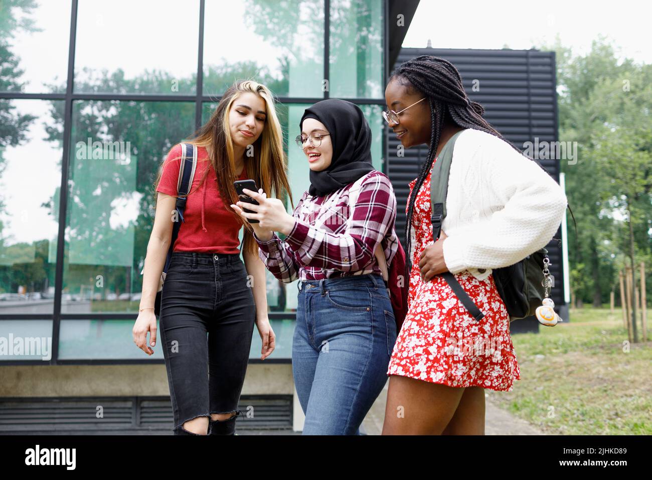 School friends hanging out in front of the campus and using a smartphone Stock Photo