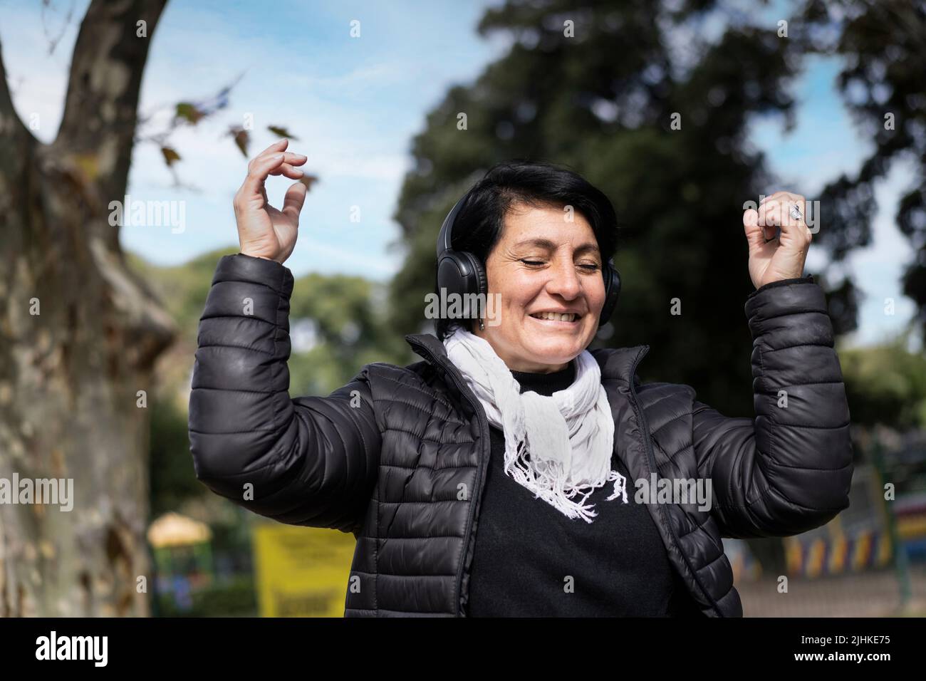 Latin woman listening to music outdoors with headphones. Expression of happiness, winning attitude. Copy space Stock Photo