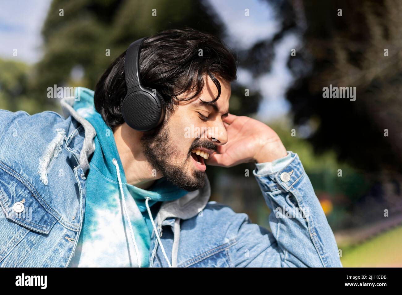 Young latin man listening to music outdoors with headphones. Expression of happiness, winning attitude. Stock Photo